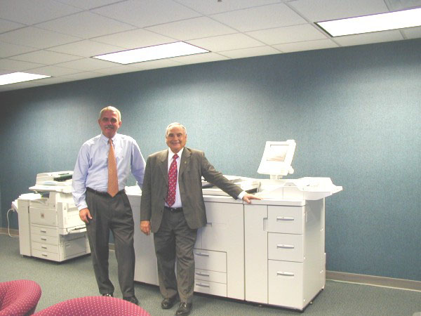 District Manager Gerry Lowe and Major Account Representative Al Spaulding of Lanier proudly pose with a LD 105, a high speed digital printing system.