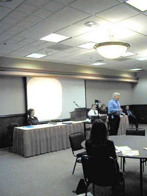 Purchasing Director Dave Tincher (seated at right) led a group of Purchasing Division representatives during a presentation on doing business with West Virginia state government. Assistant Director Curt Curtiss (standing) explained the bid process.